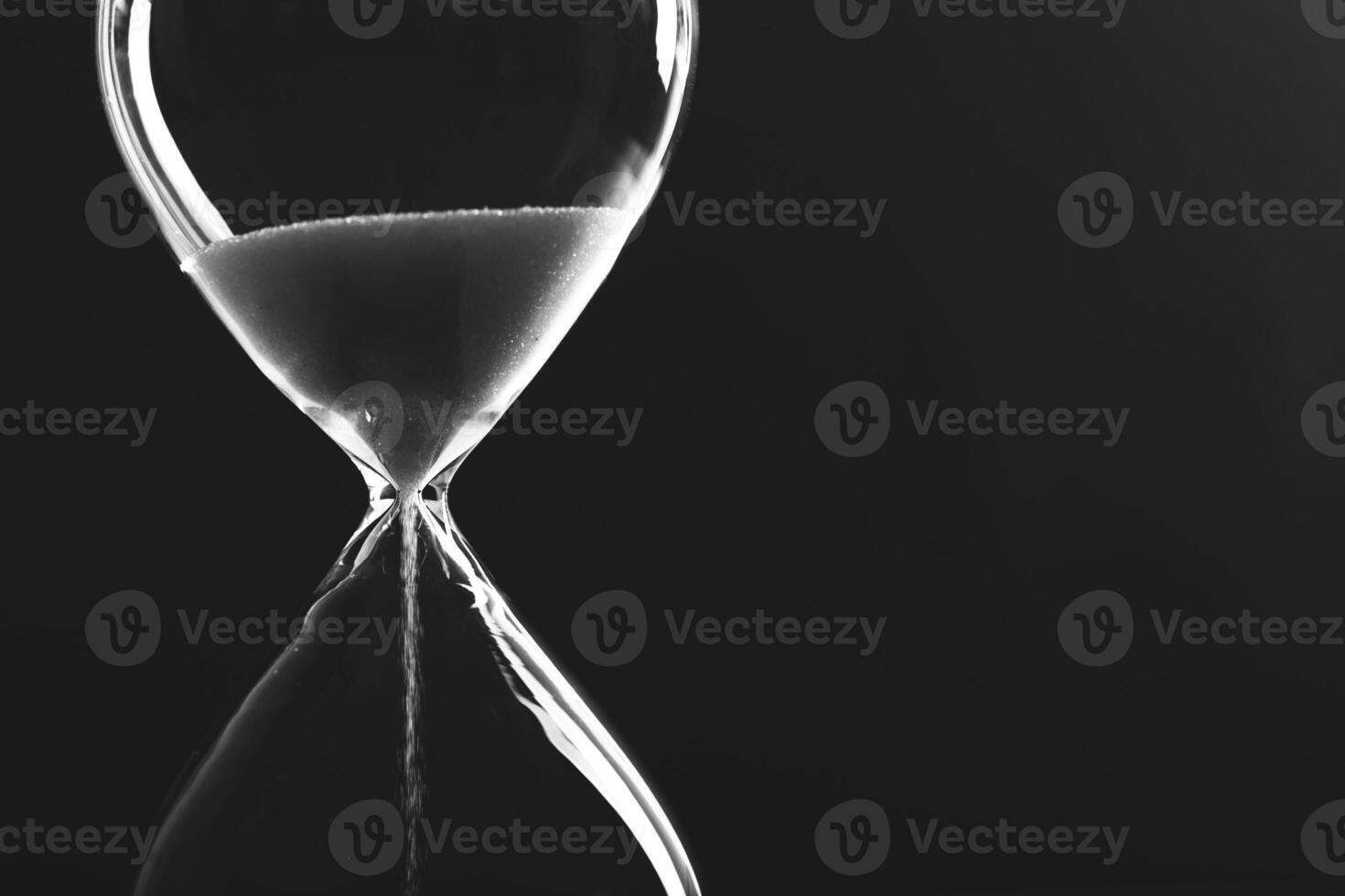Vintage hourglass filled with sand captures the essence of time flowing quietly in minimalist black and white setting photo