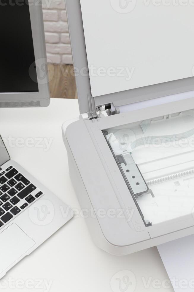 Office workspace showing a scanner with a laptop and a minimalistic environment during the day photo