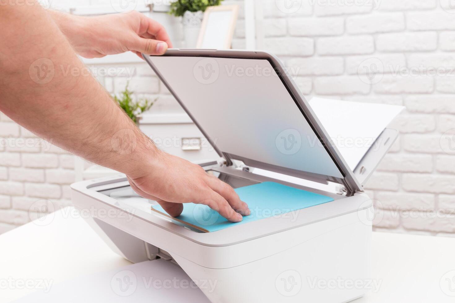 Hands placing a blue sheet on a scanner in a modern, bright workspace during the day photo