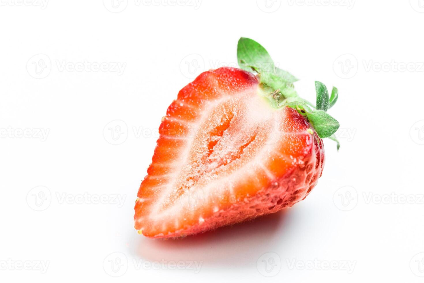 Freshly sliced strawberry showing vibrant red color and green leaves, perfect for desserts or healthy snacks photo