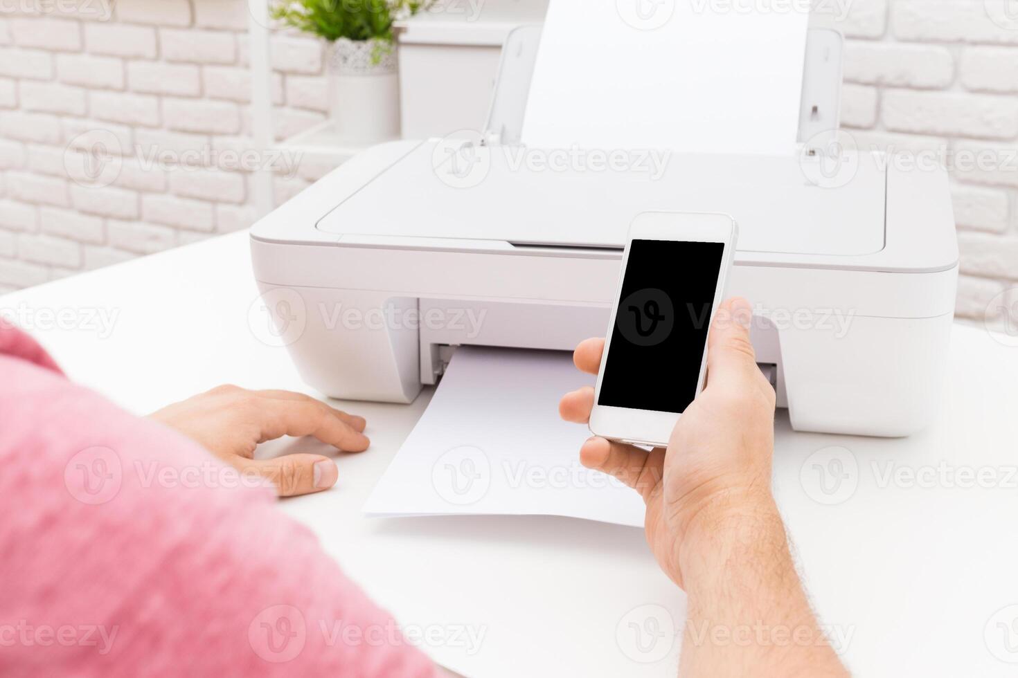 Person using smartphone to print document from printer in modern workspace photo