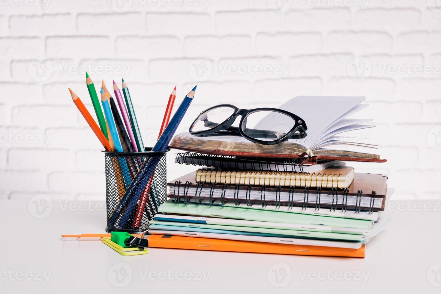 Colorful stationery and books arranged neatly on a desk with reading glasses beside them photo