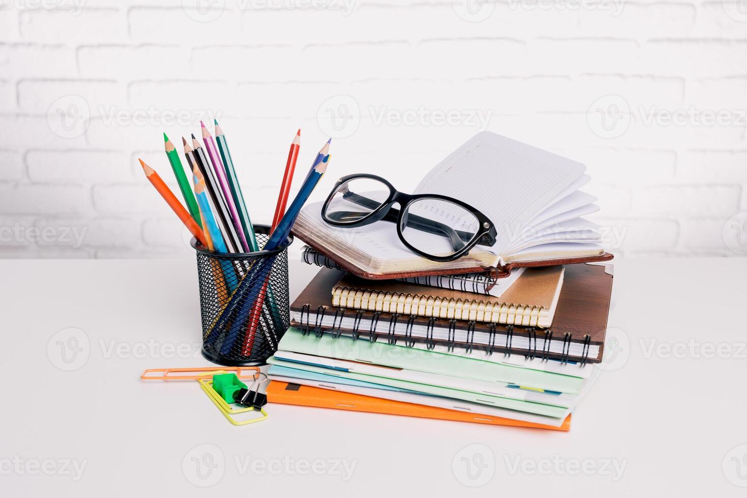 Colorful stationery items and glasses arranged on a desk with notepads ready for studying or creative work in a bright environment photo