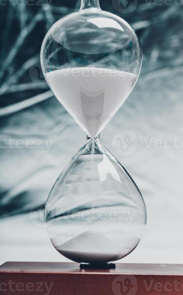 Elegant hourglass with fine white sand flowing, symbolizing the passage of time in a minimalist setting photo