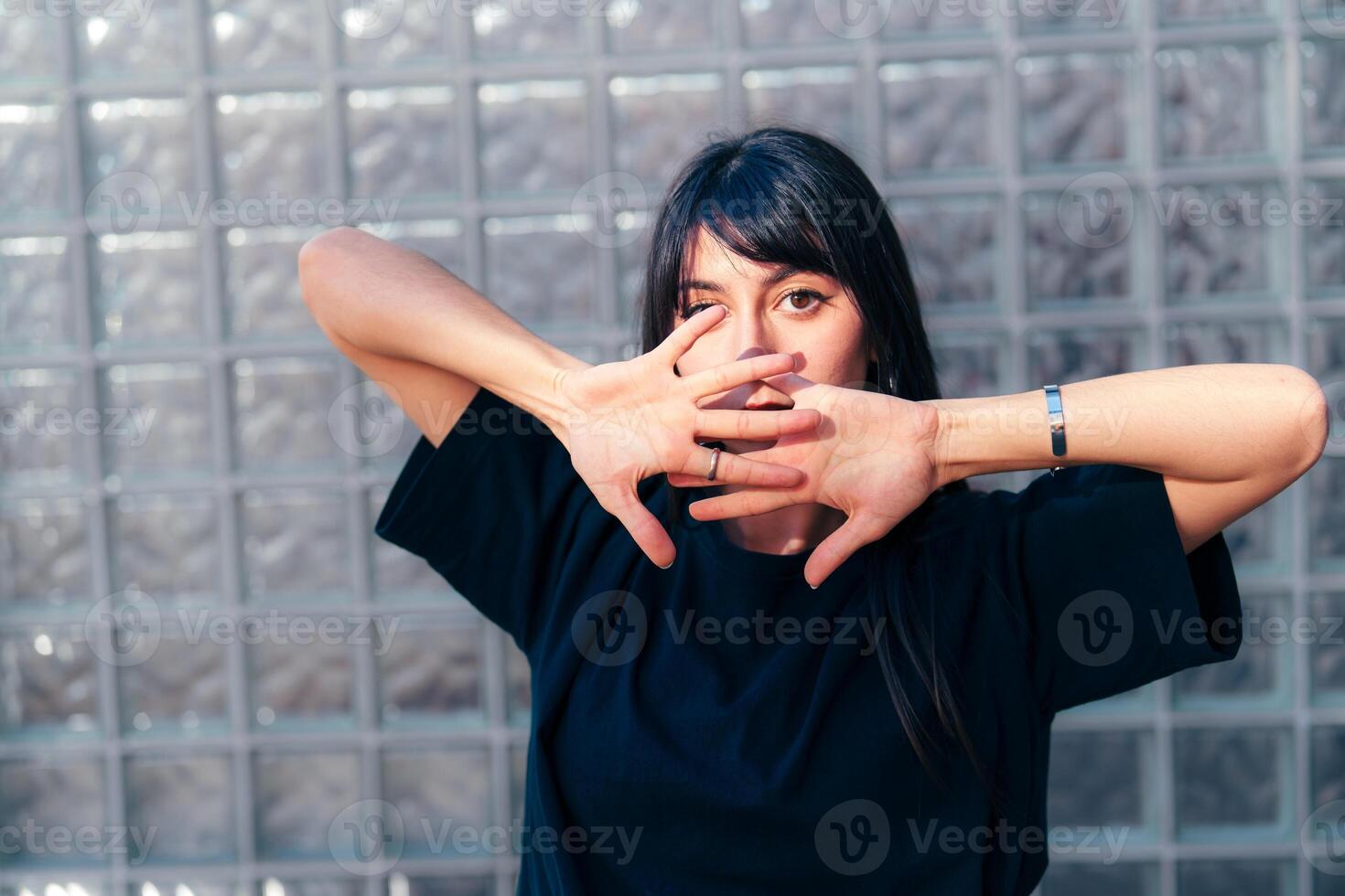 Woman performing expressive dance moves in a contemporary setting with textured glass background photo
