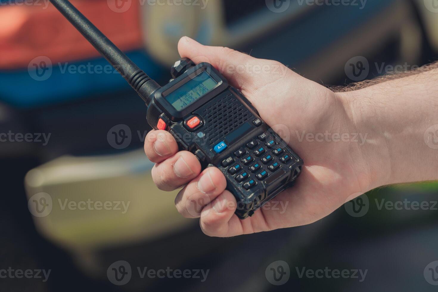 Handheld radio communication device being used outdoors during daylight in a rural setting photo