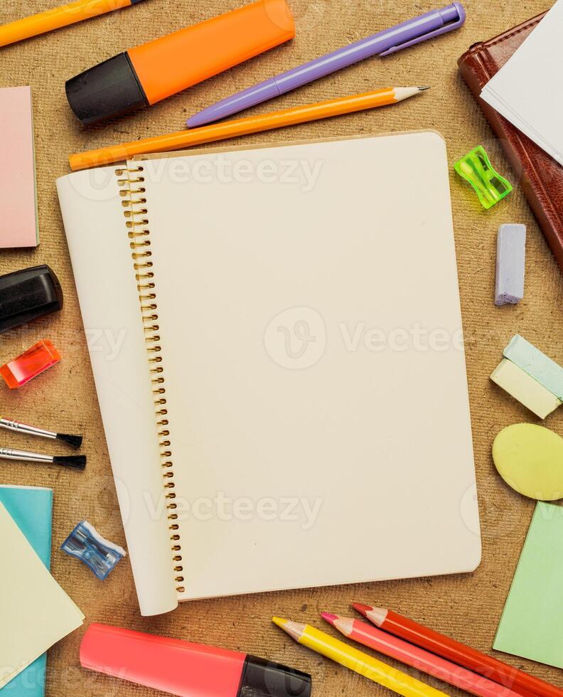 Creative workspace with blank spiral notebook and colorful stationery on wooden desk photo
