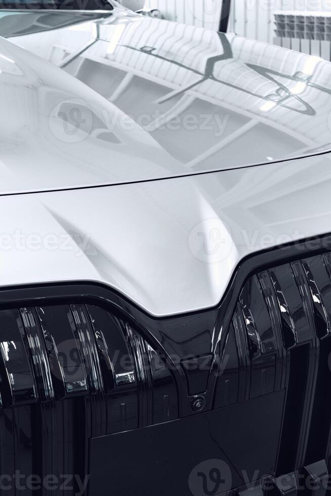 Close-up view of a modern car front showcasing sleek design and shiny chrome details in a well-lit indoor setting photo