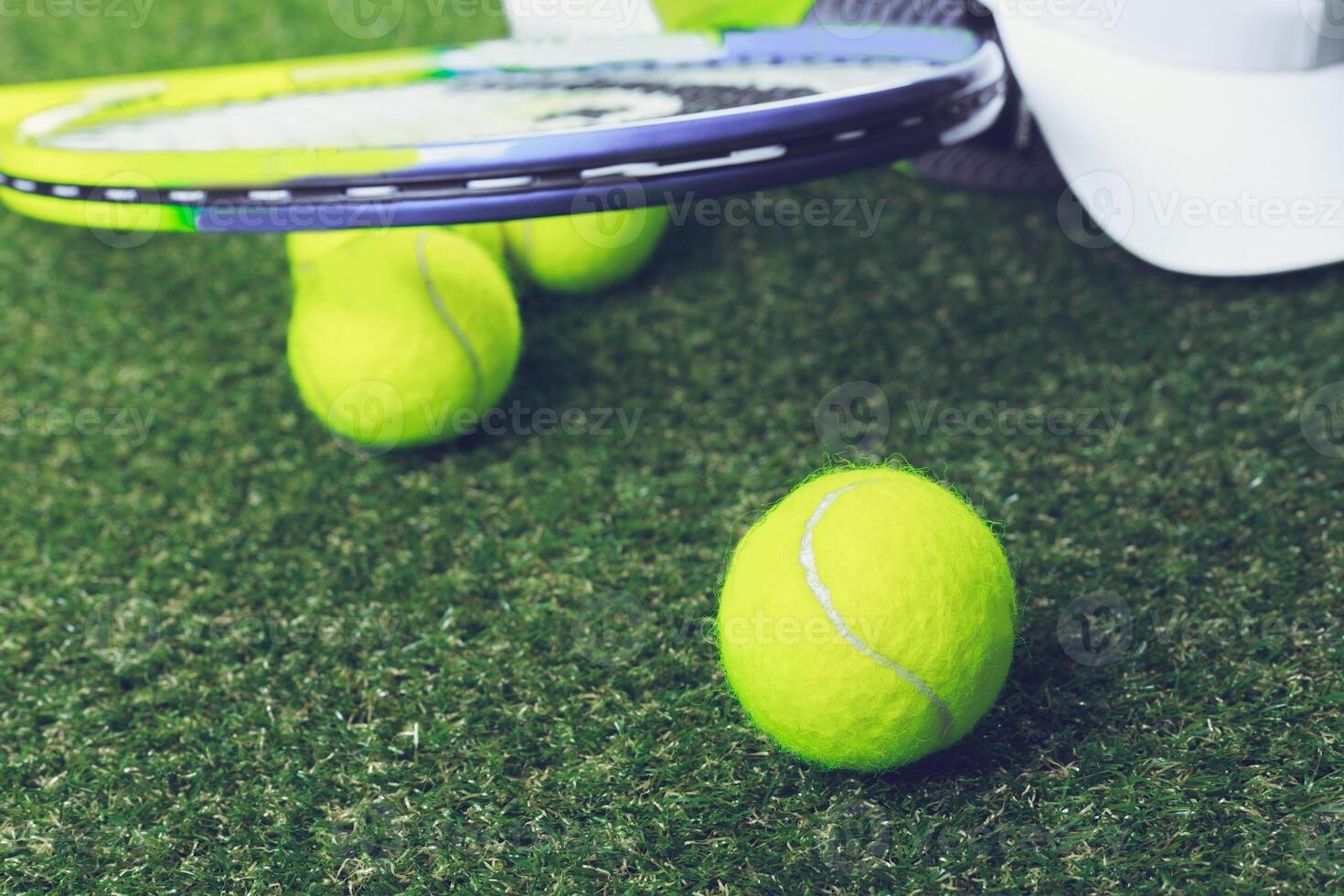 Tennis balls scattered on green turf near a racket during a practice session in daylight photo