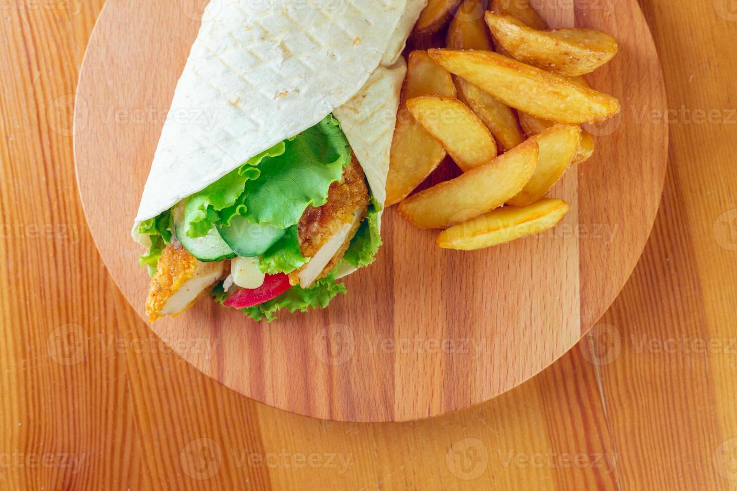 Delicious wrap filled with fresh vegetables and crispy chicken accompanied by golden fries photo