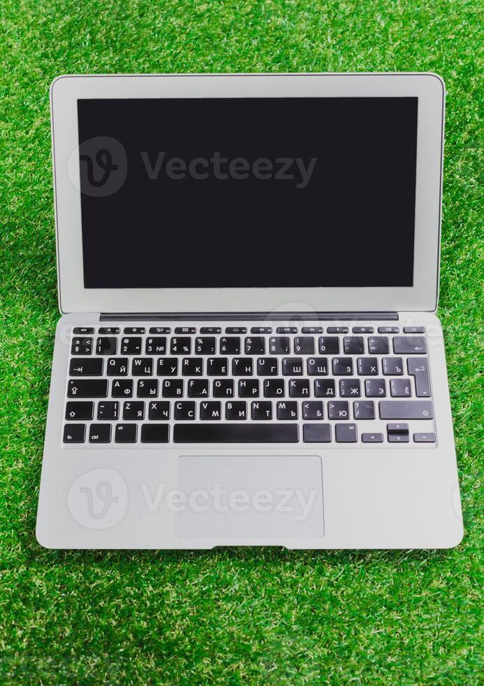 Laptop placed on green grass surface ready for outdoor work or leisure activities in a bright environment photo