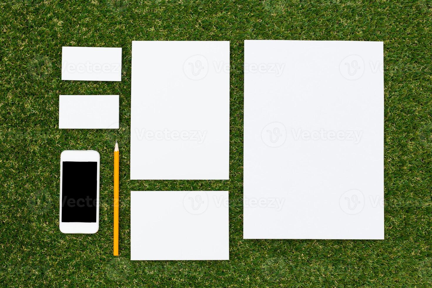 Various sizes of blank paper and a smartphone arranged on green grass for creative planning and brainstorming photo