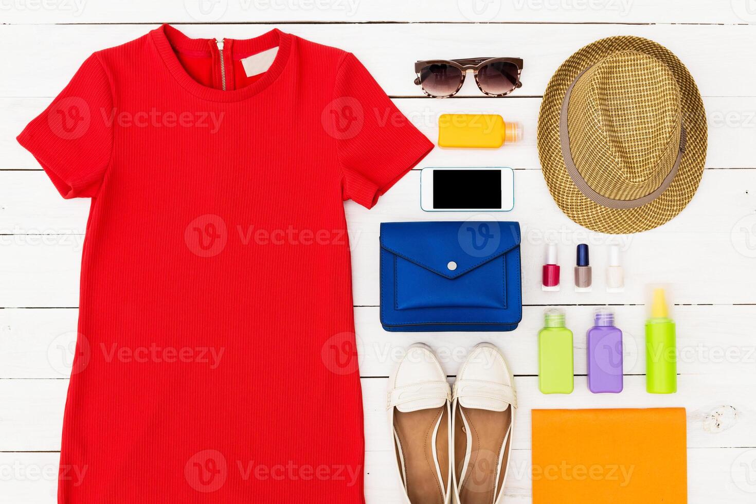 Bright red dress and various summer accessories arranged neatly on a wooden surface photo