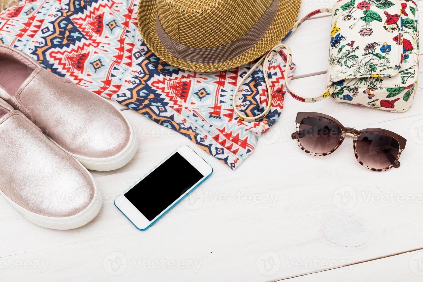 Stylish summer accessories arranged on a flat surface with a colorful bag, shoes, hat, sunglasses, and smartphone ready for a day out photo