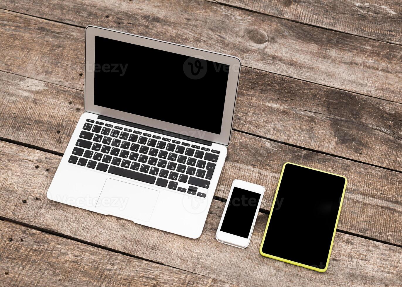 Various electronic devices arranged on a rustic wooden table during daylight photo