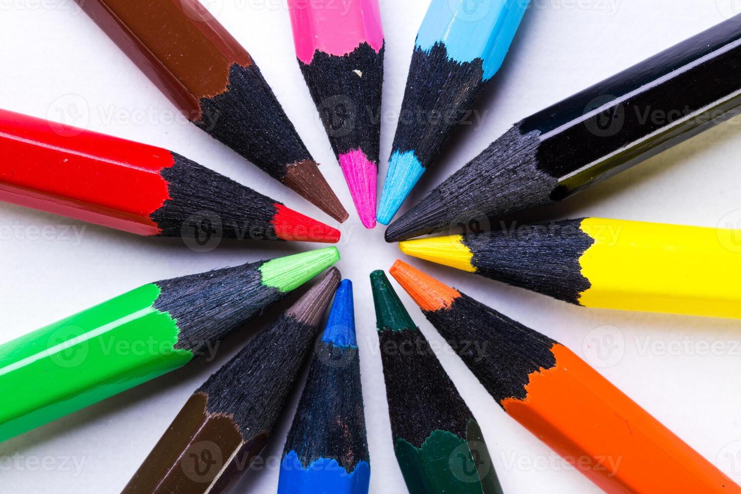 Vibrant colored pencils arranged in a circle showcasing their sharpened tips on a white surface photo