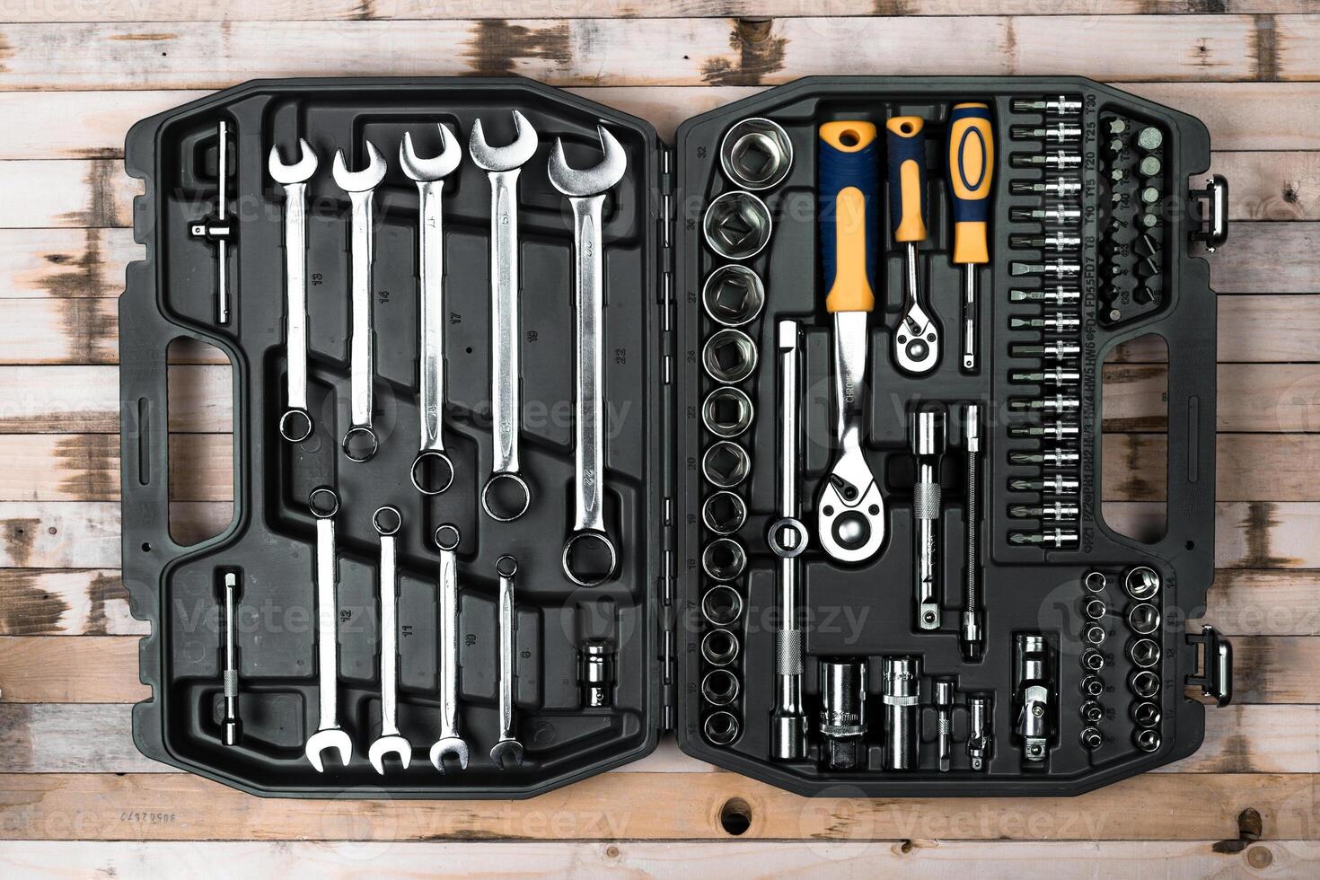 Tool set arranged neatly in a black case on a wooden surface showcasing a variety of wrenches and sockets photo