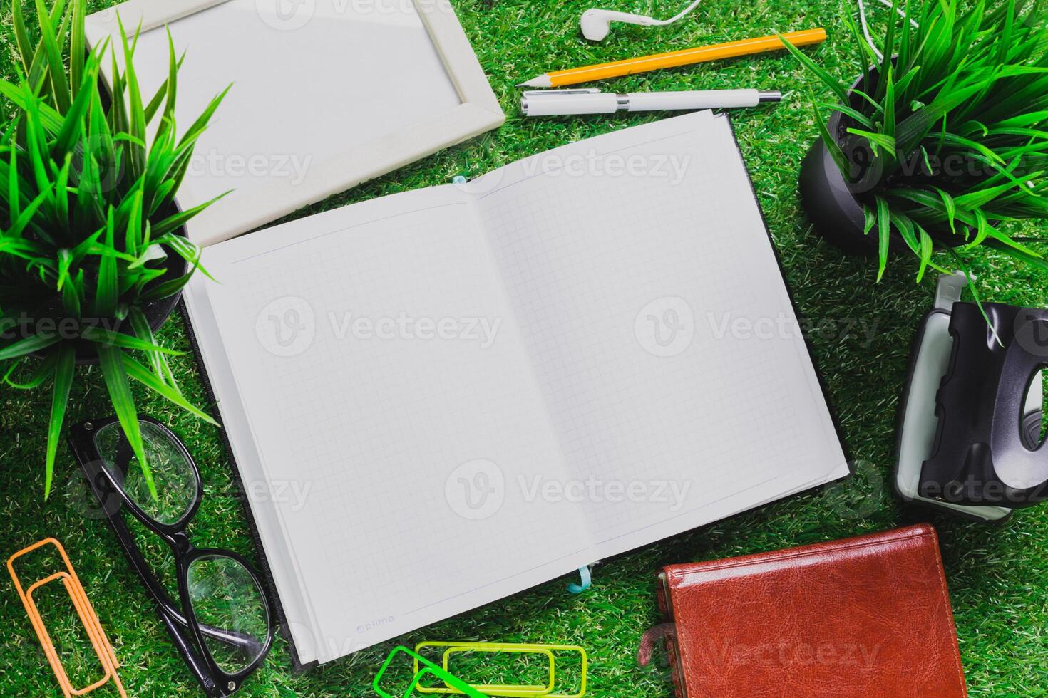 Creative workspace setup featuring an open notebook, stationery, and green plants in a light and inviting environment photo