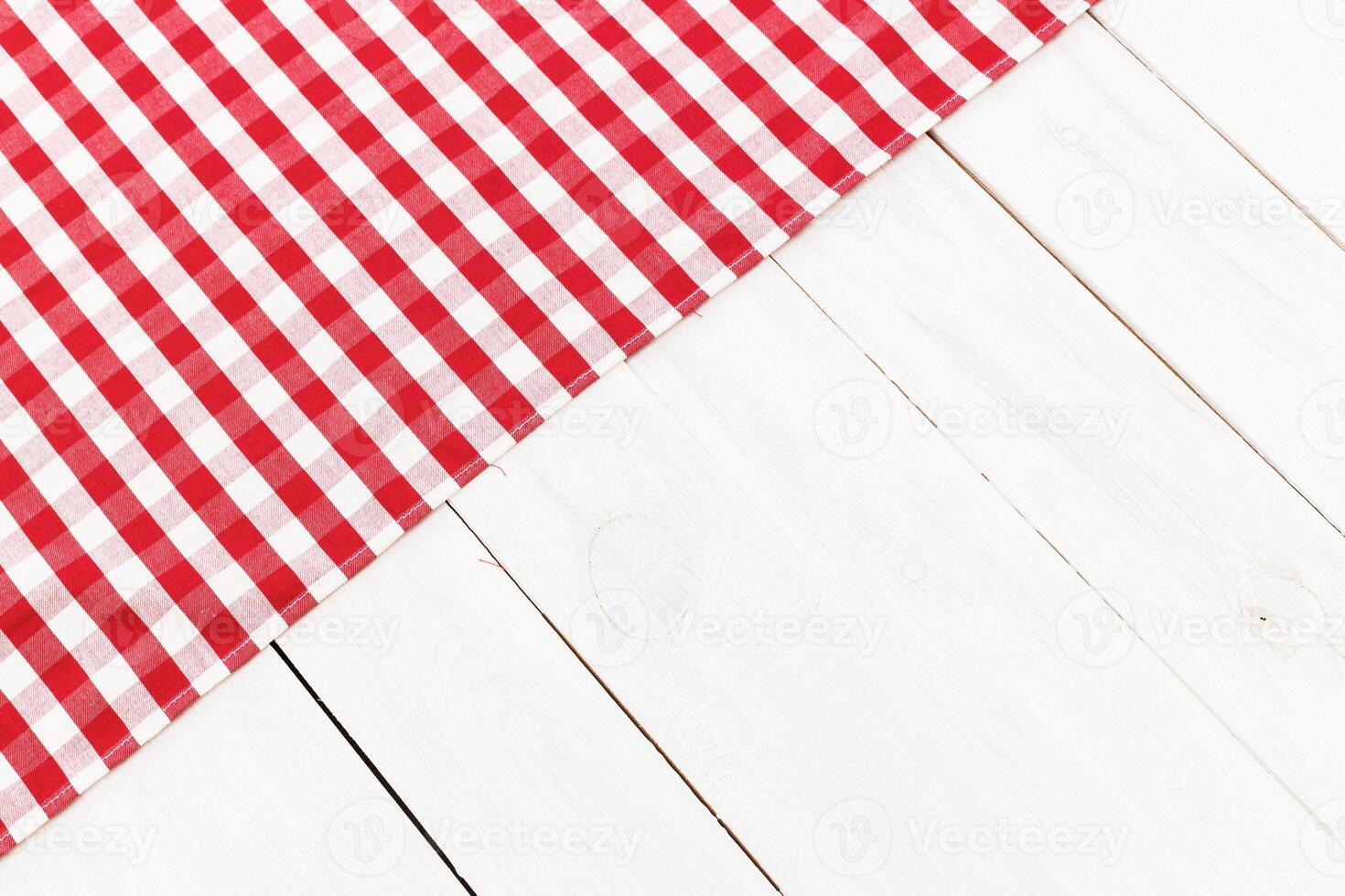 Table setting on a white wooden surface with a red and white checkered cloth for a casual dining experience photo