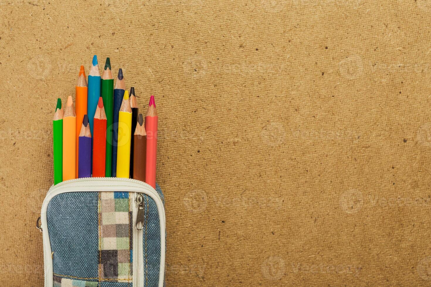 Colorful colored pencils arranged in a pencil case against a textured background in a workspace photo