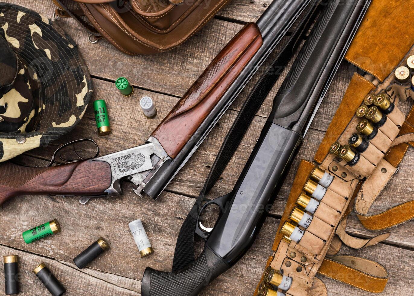 Collection of hunting firearms and accessories laid out on a rustic wooden table photo