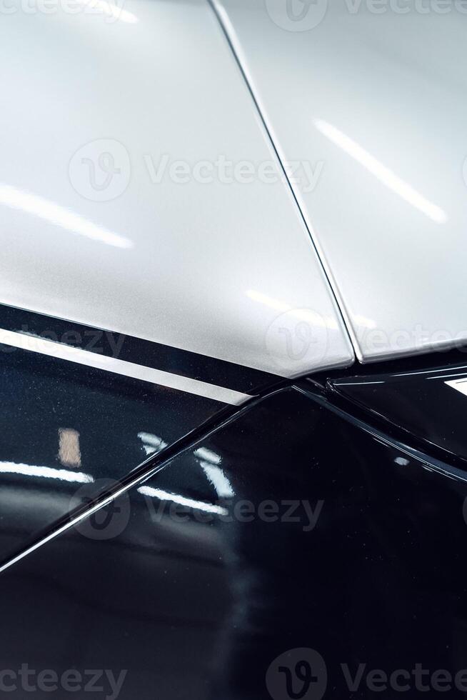 Detailed view of a sleek car body showcasing a striking black and white design in a well-lit garage environment photo
