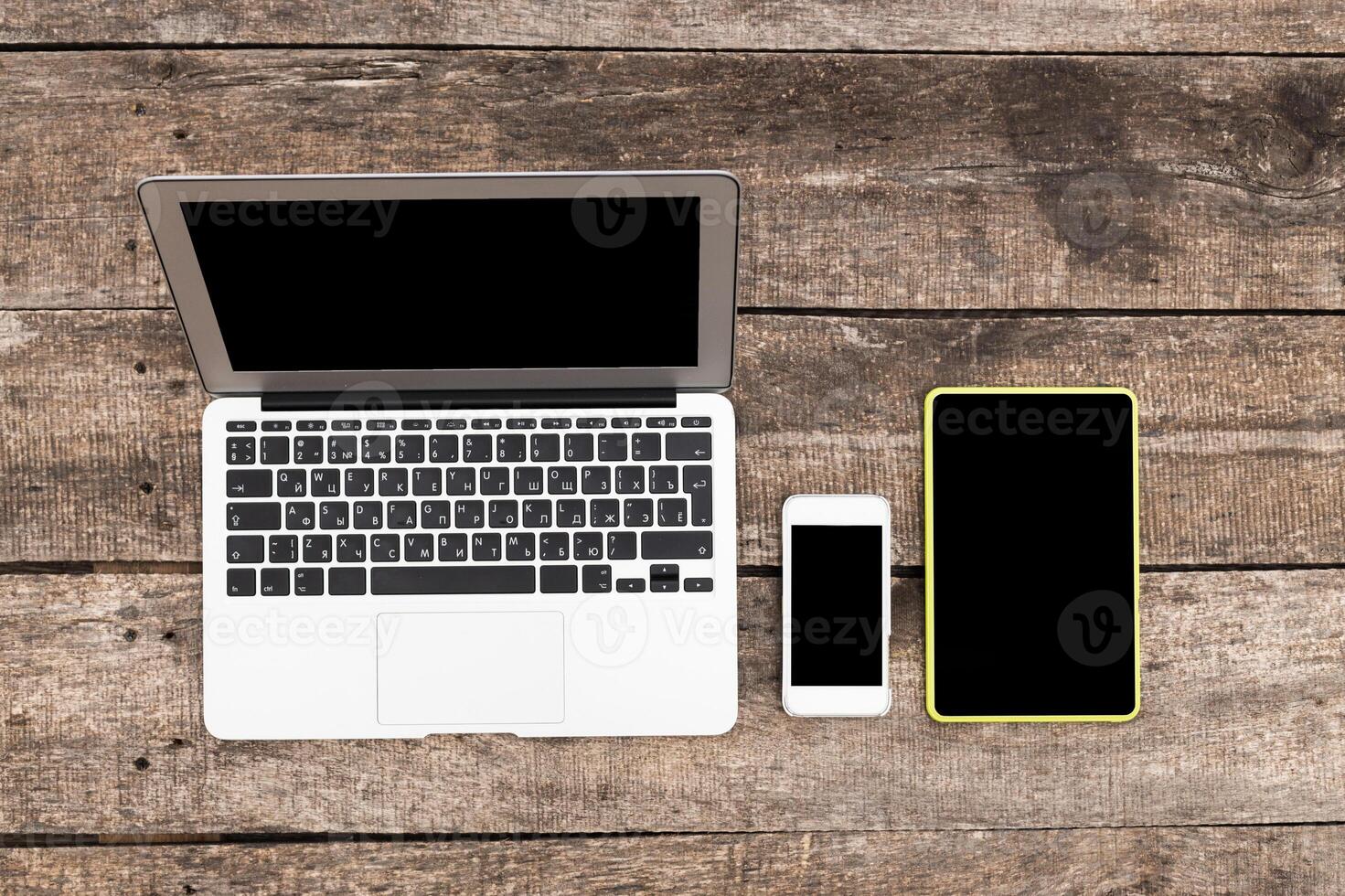 Laptops, tablets, and smartphones arranged on a wooden table for digital workspace setup photo