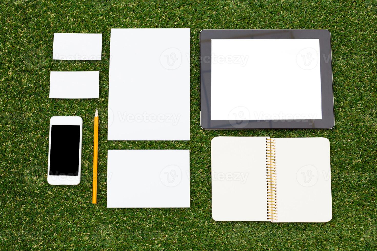 Creative workspace setup with stationery on grass during a sunny day photo