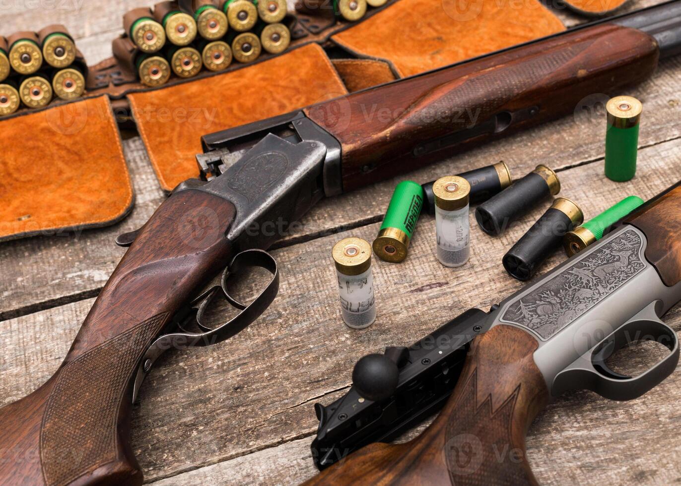 Rifles and shotgun shells arranged on a rustic wooden surface for ammunition preparation and hunting activities photo