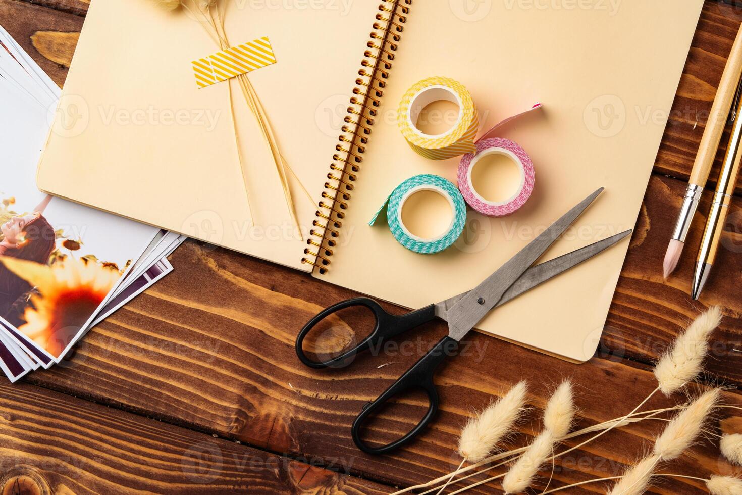 Crafting materials arranged on a wooden table with scissors, tape, and a notebook for creative projects photo
