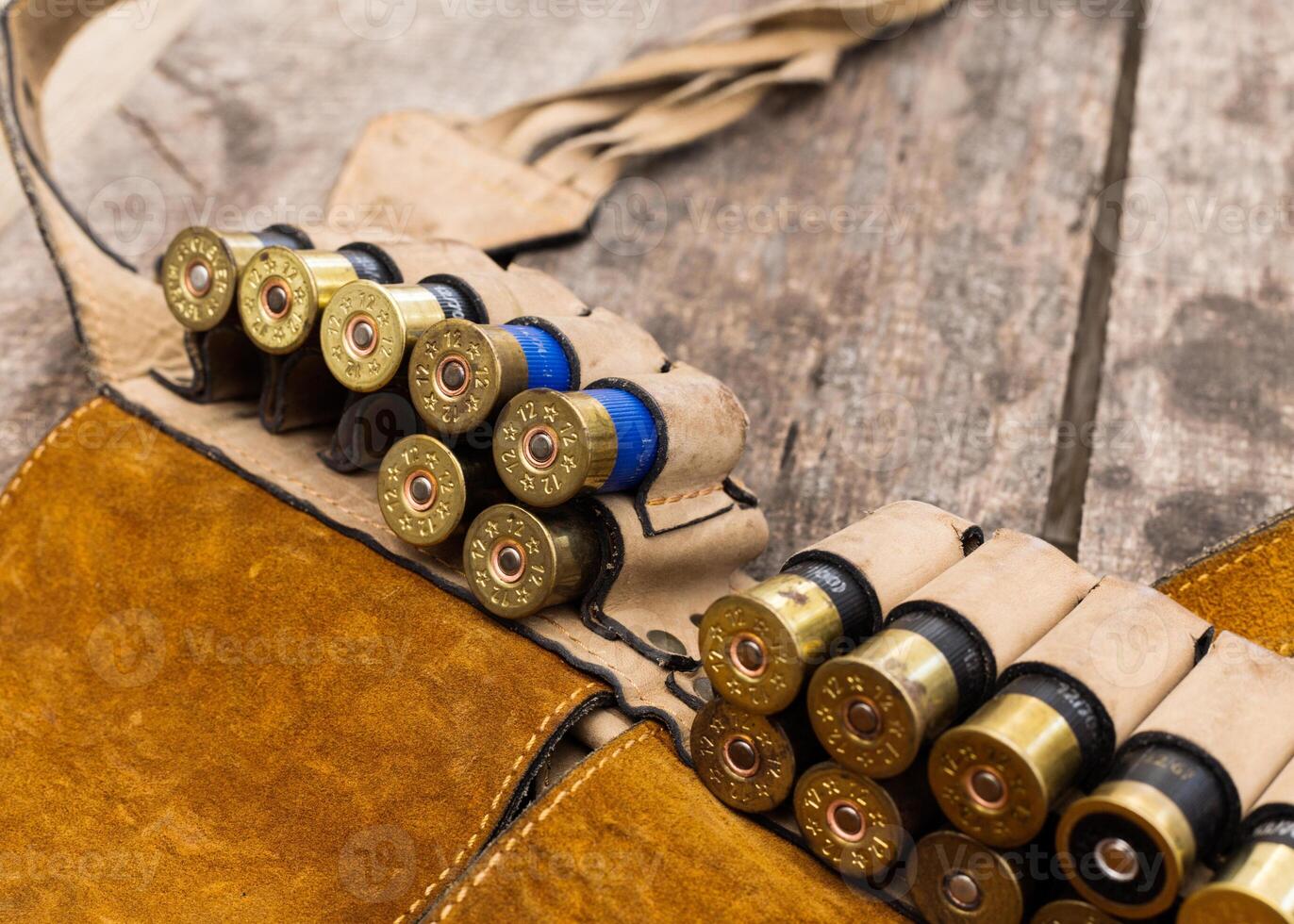 Shotgun shells arranged neatly in a leather ammo pouch on a rustic wooden surface photo
