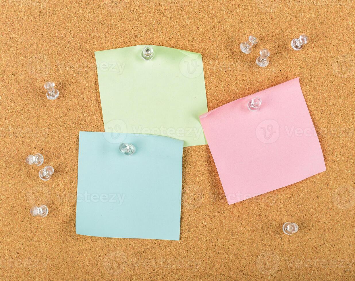 Colorful sticky notes pinned on corkboard with pushpins in an organized workspace for reminders photo