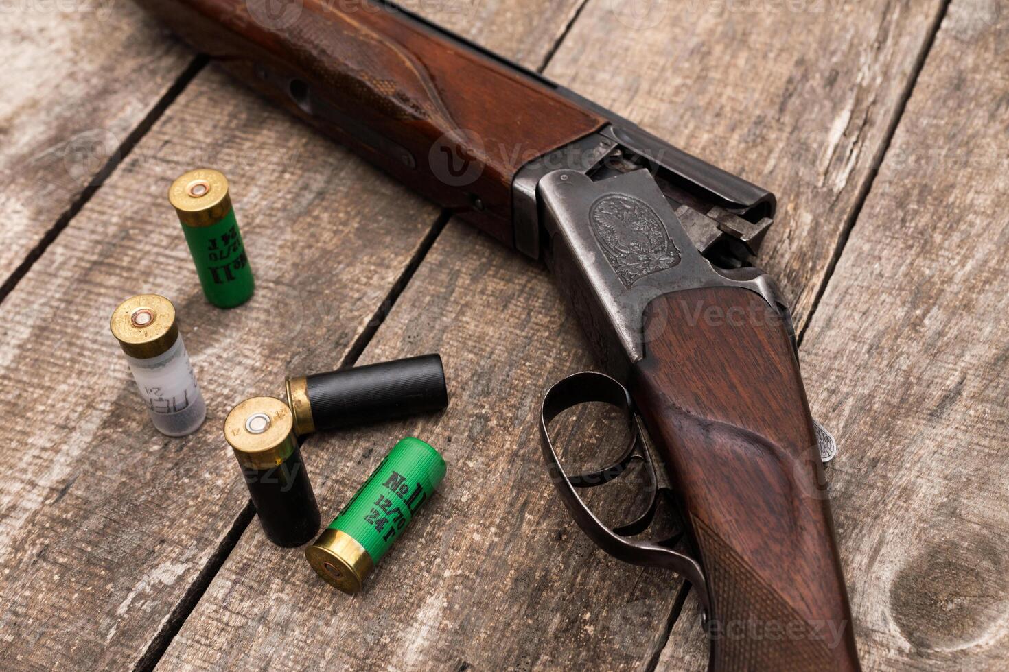 Vintage shotgun surrounded by ammunition on wooden surface, highlighting craftsmanship and utility in hunting photo