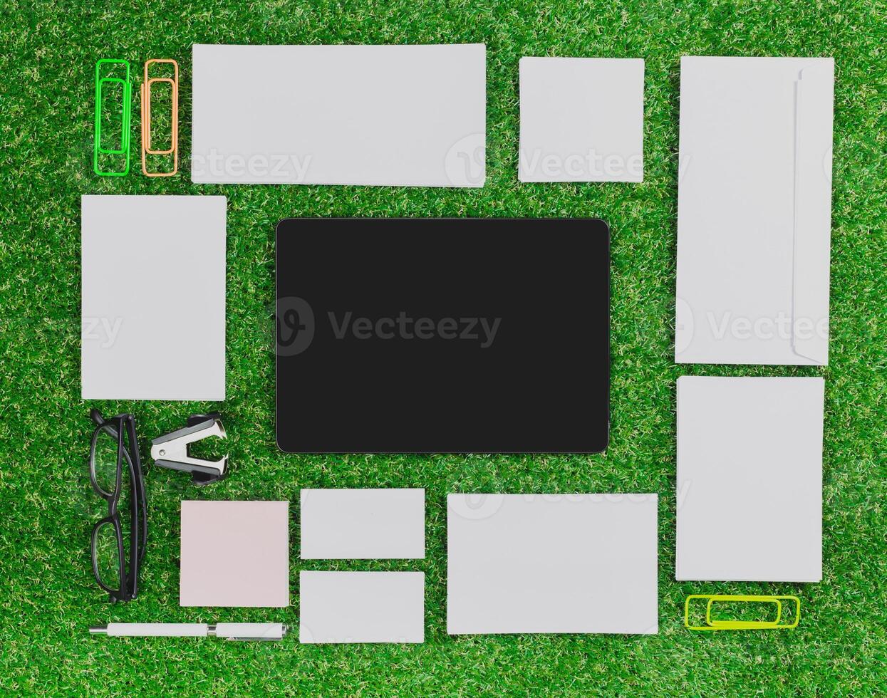 Office workspace layout with stationery items on green turf background during daylight photo