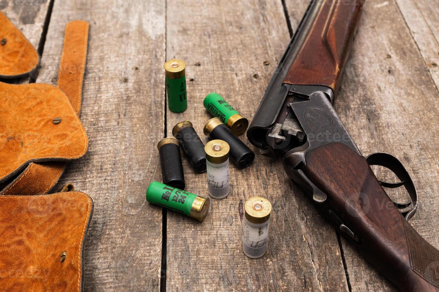 Shotgun and ammunition arranged on a wooden surface in an outdoor setting, showcasing hunting essentials and readiness for the field photo