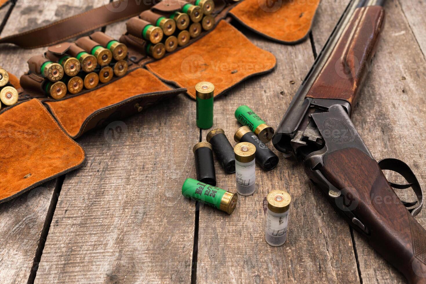 Shotgun and ammunition arranged on a wooden surface ready for hunting or shooting practice in an outdoor setting photo