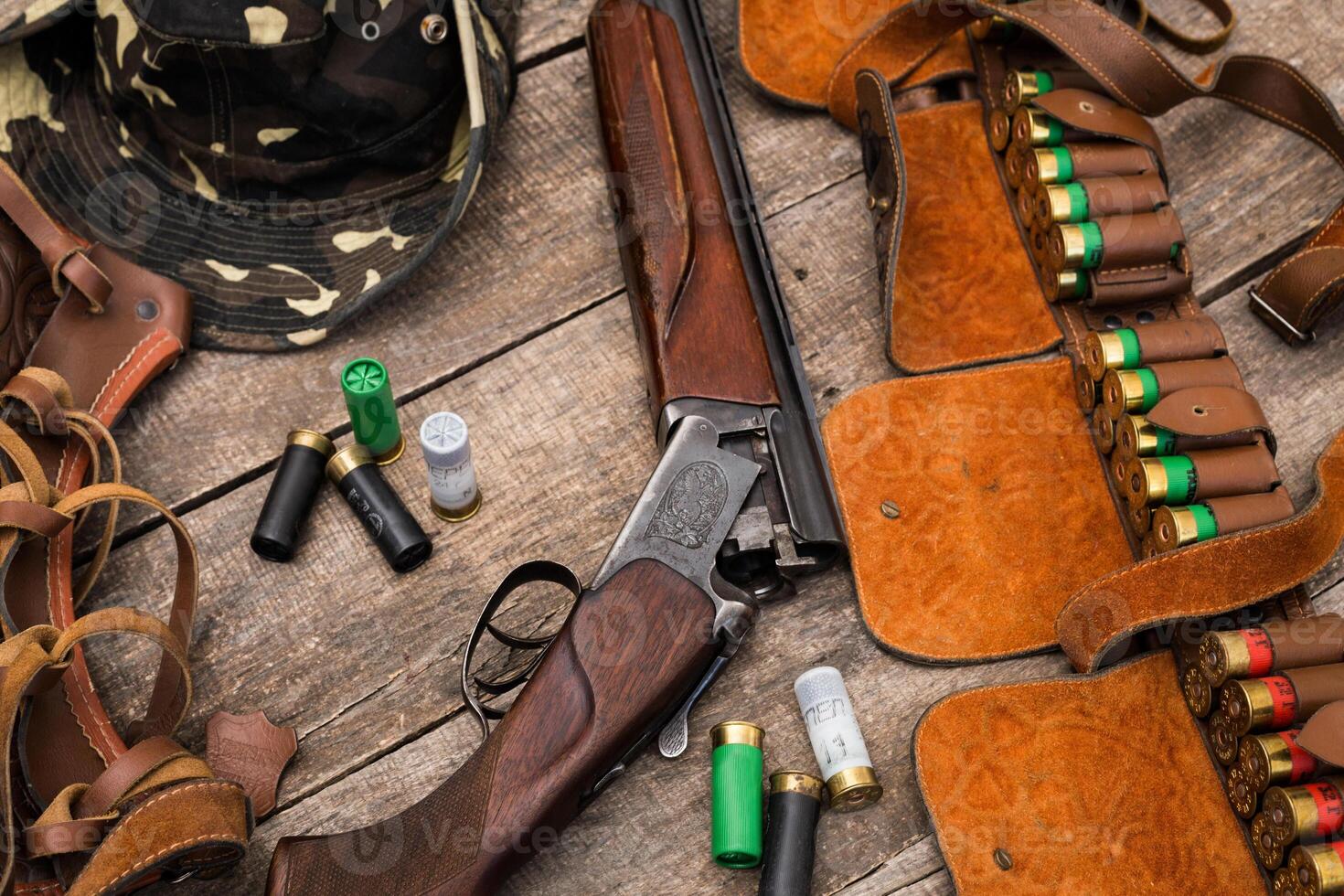 Hunting equipment arranged on a wooden surface with camouflage gear and shells in the early morning light photo