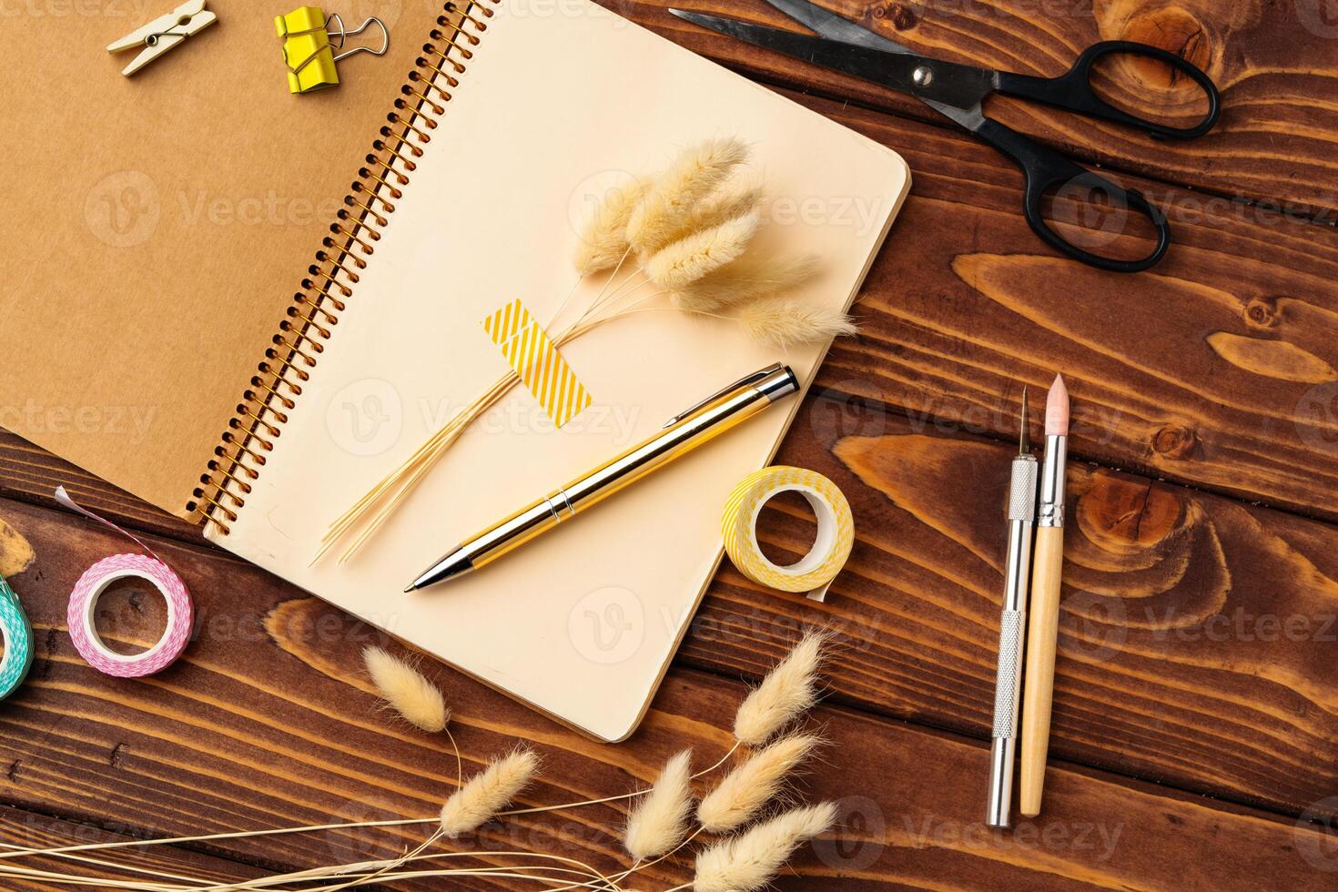 Creativity in progress with stationery, dried flowers, and crafting tools on a wooden workspace photo