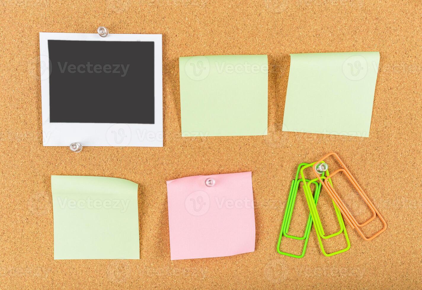 Colorful sticky notes and a blank photo frame arranged on a corkboard for reminders and organization
