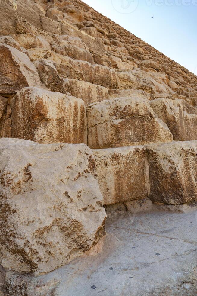 Exploring the ancient stone steps of the Great Pyramid near Giza under a clear blue sky photo