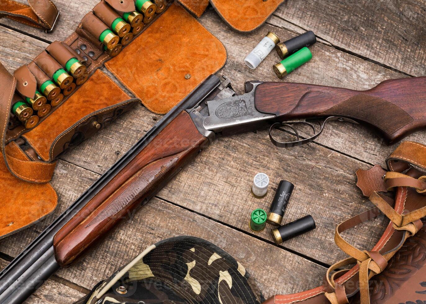 Wood and metal shotgun with ammunition on wooden table displayed for hunting enthusiasts in a rustic environment photo