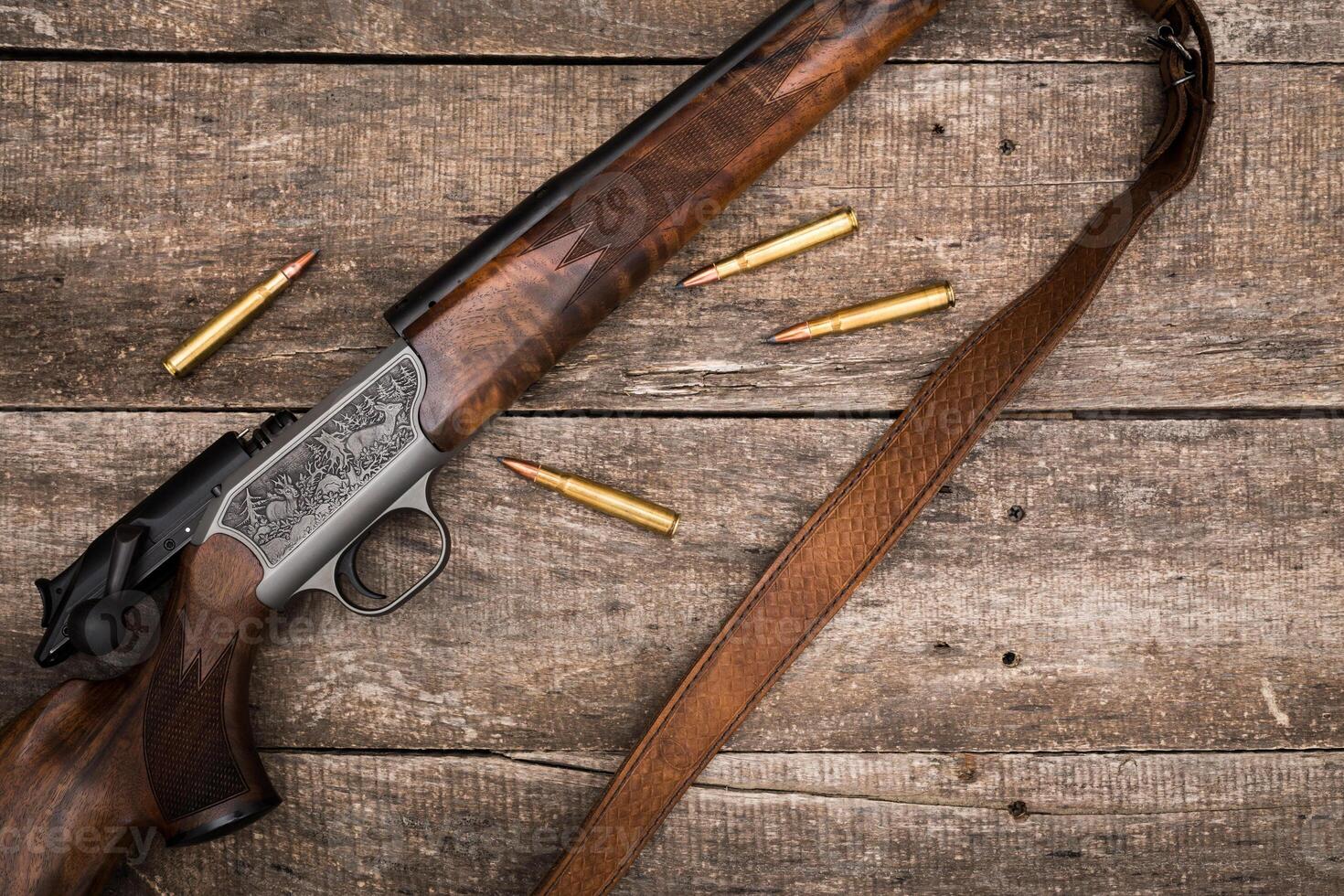 Detailed wooden hunting rifle on rustic wood table with ammunition scattered around photo