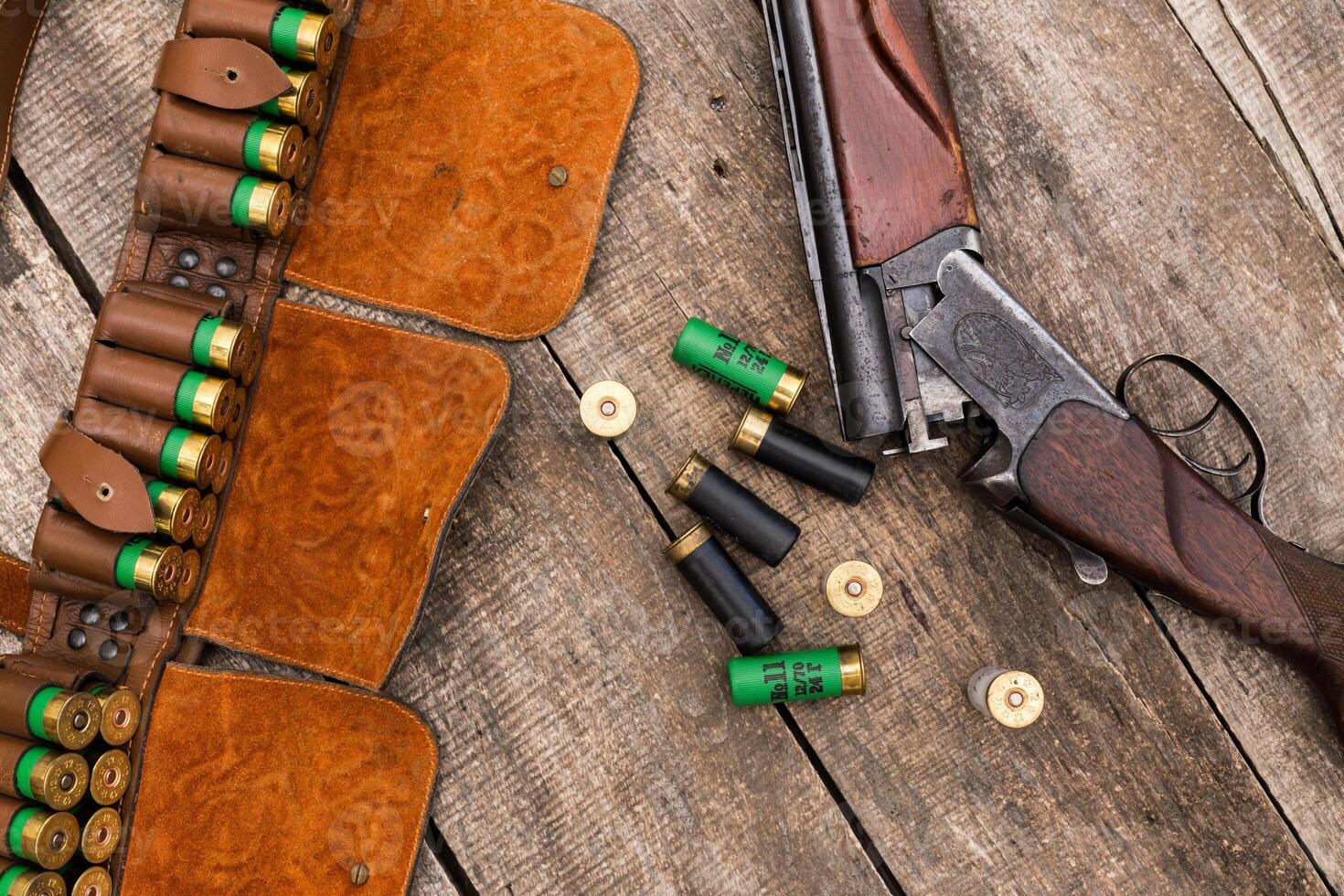 Shotgun with ammunition laid on a rustic wooden surface during a hunting trip in autumn photo