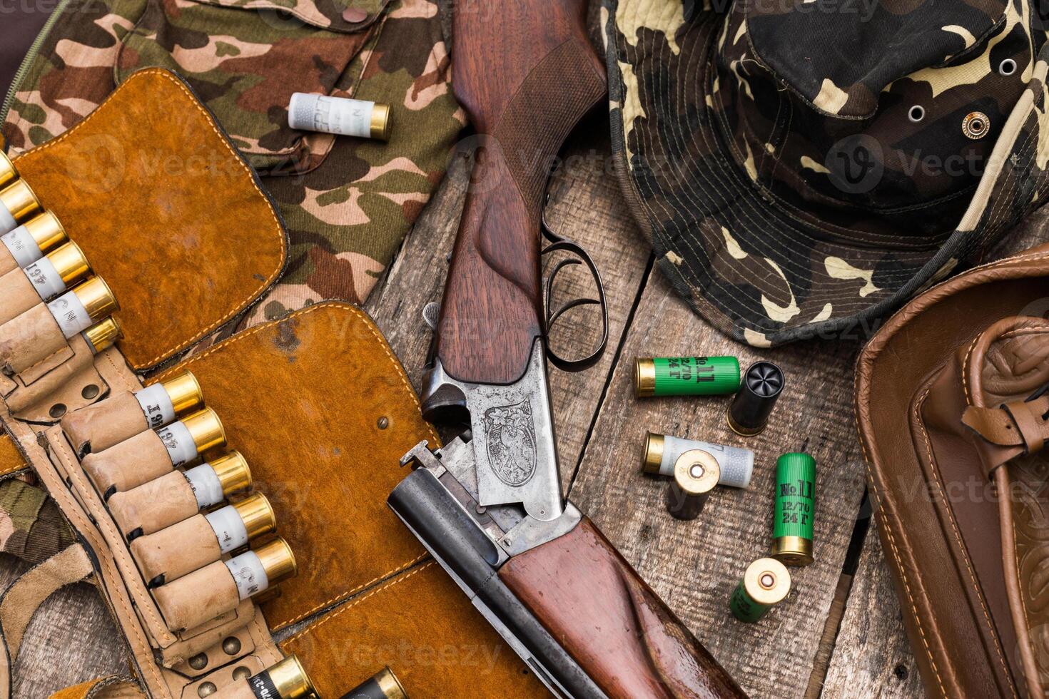 Hunting equipment arranged on a wooden surface with camouflage gear and shells in the early morning light photo