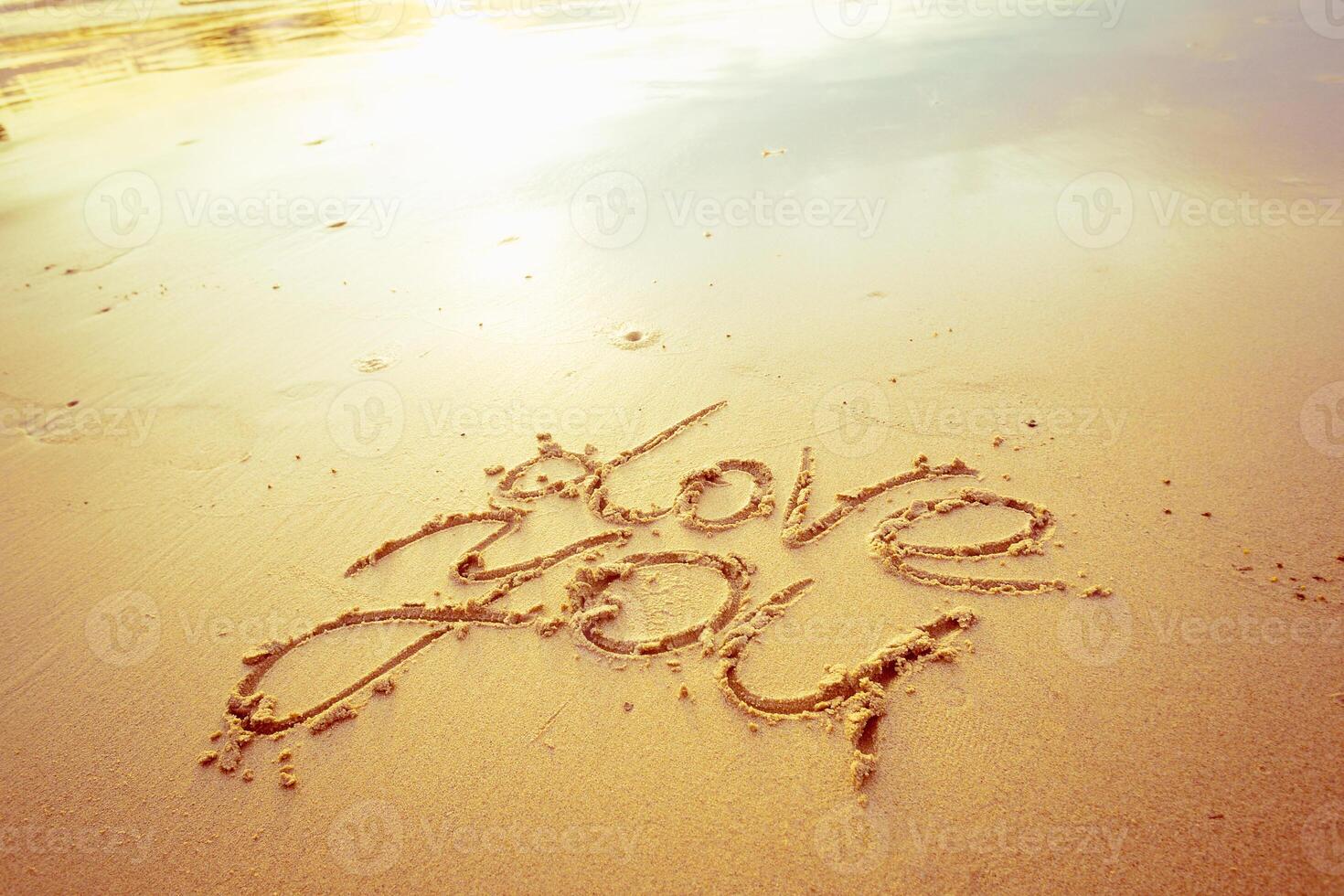 Writing love messages in sand on a beach during sunset creates a romantic atmosphere photo