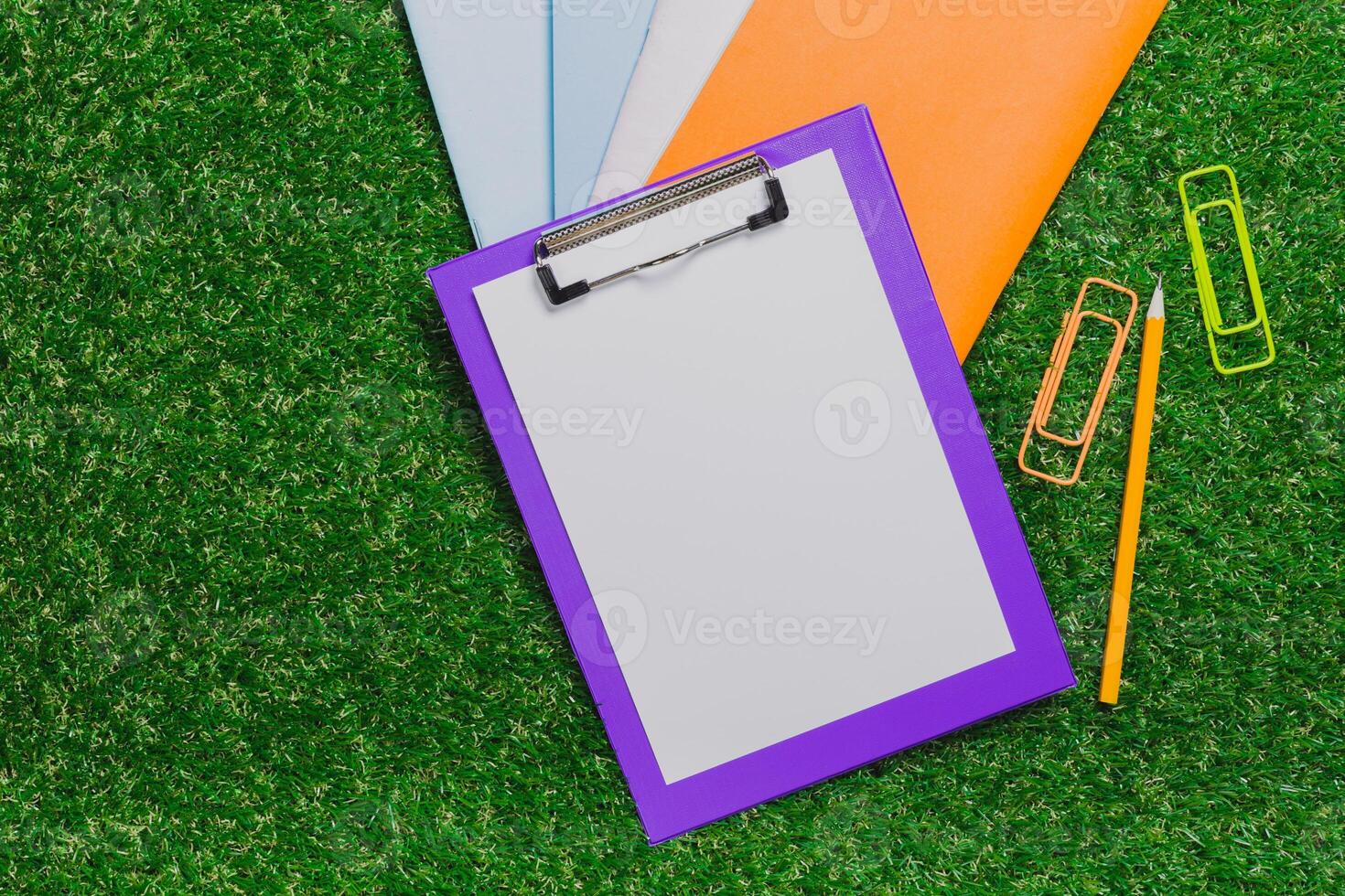 Colorful stationery supplies arranged on synthetic grass for a vibrant workspace setup photo