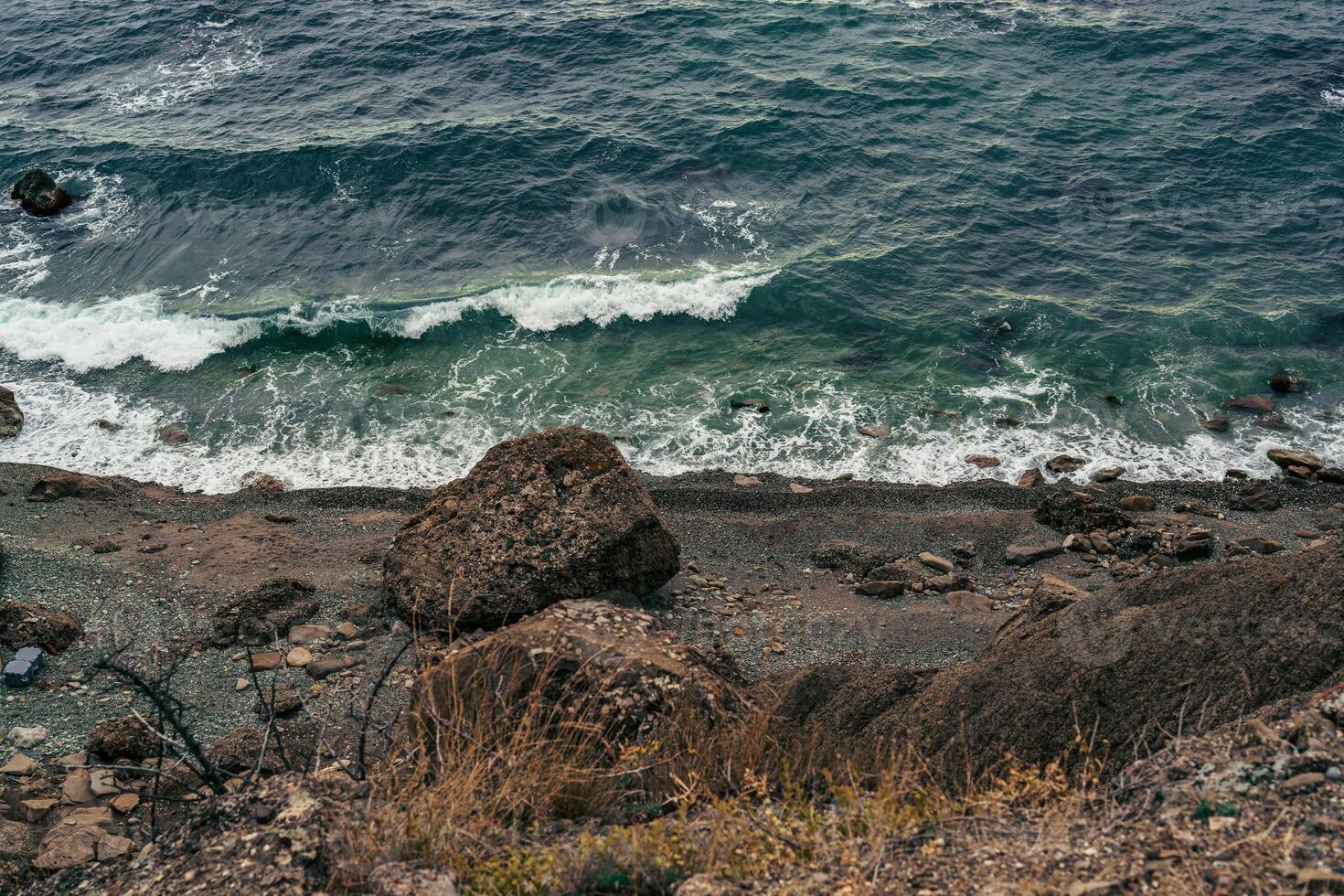 Waves crashing on a rocky shoreline under a cloudy sky during the early evening in a coastal landscape photo