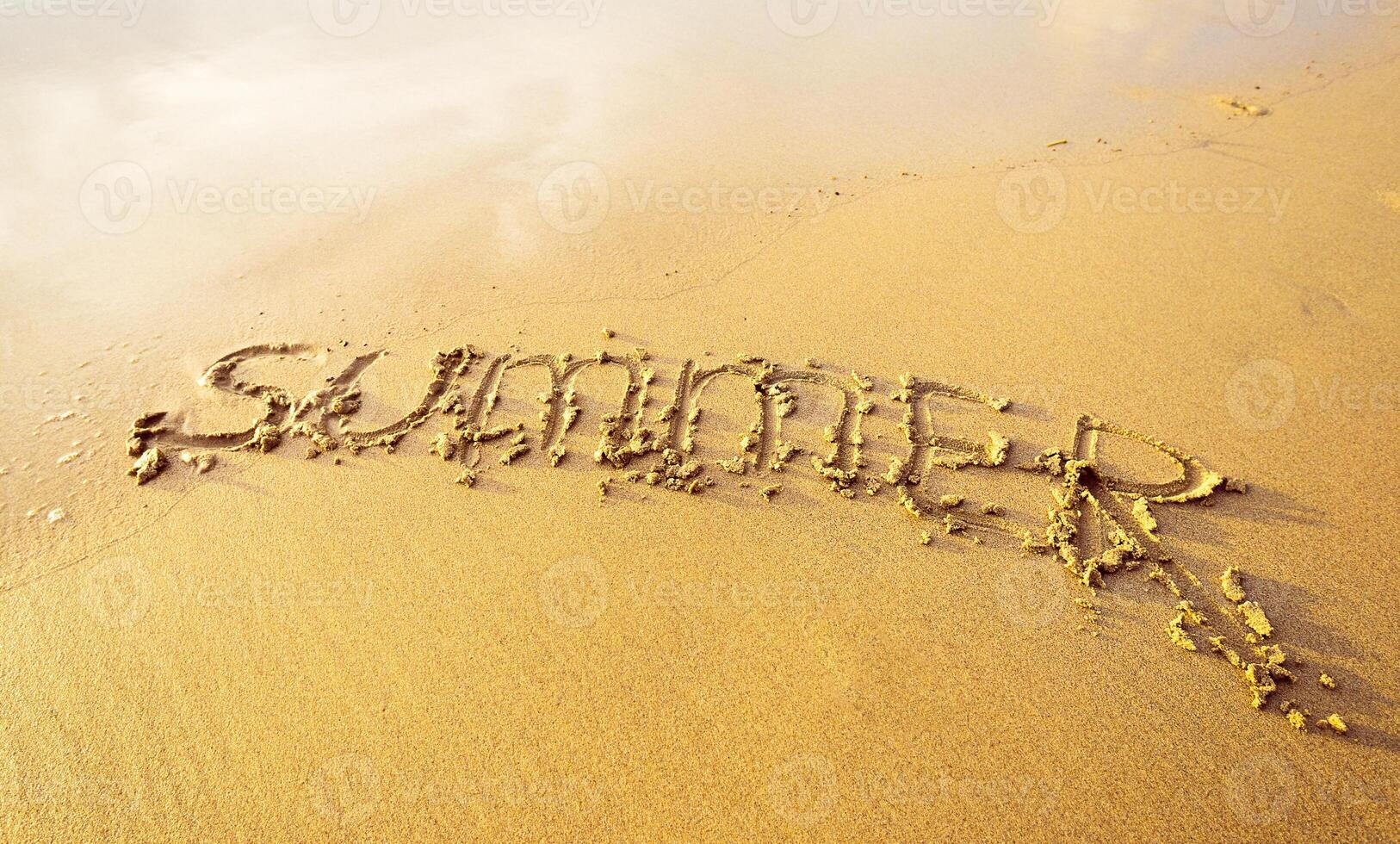Writing summer in sand on a sunny beach reflecting the joy of warm weather and vacation vibes photo