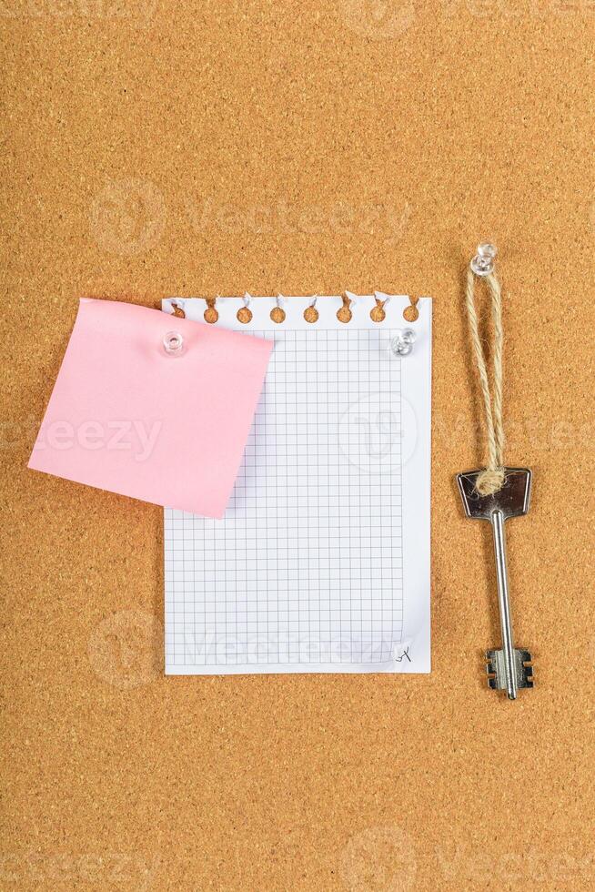 Document holder with a note and key on a cork bulletin board photo