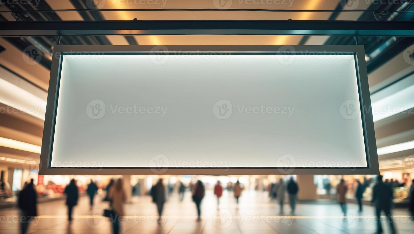 Modern shopping center interior with illuminated sign and blurred shoppers in background during busy daytime hours photo